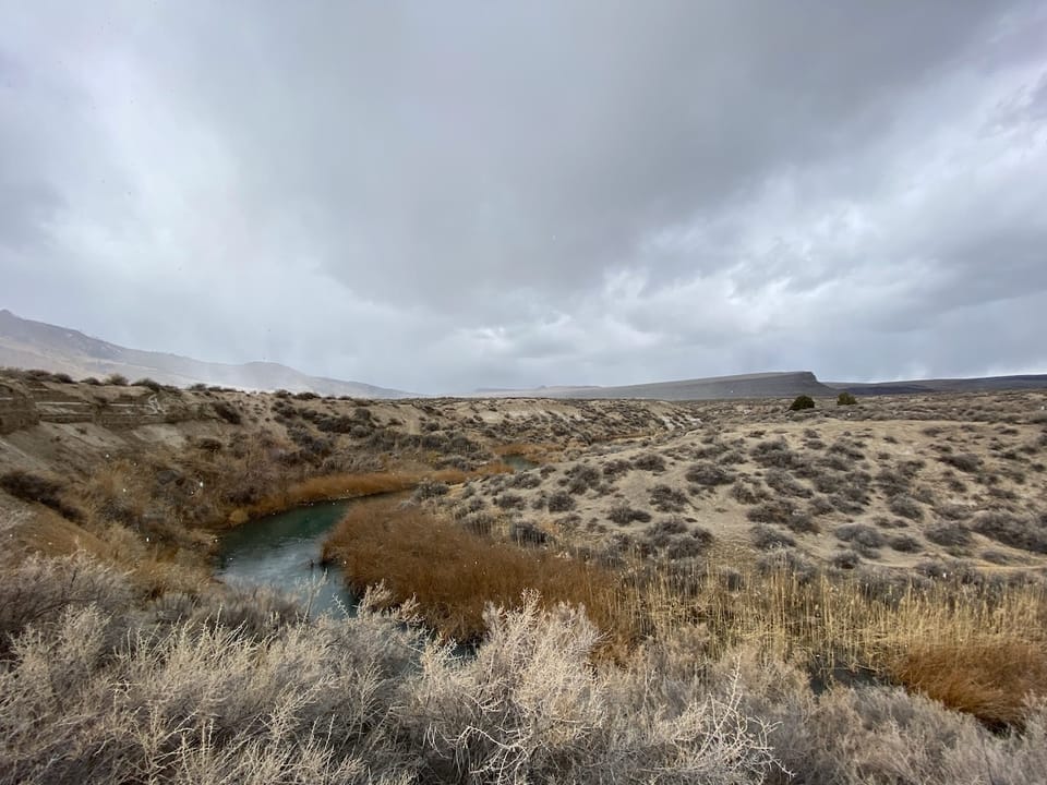 High desert landscape with a river and clouds.